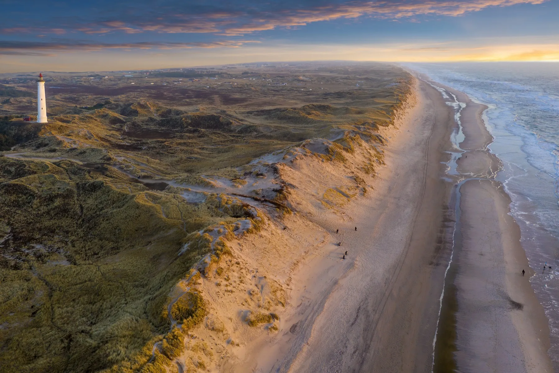 Danish coastline with dunes, beach and lighthouse at sunset